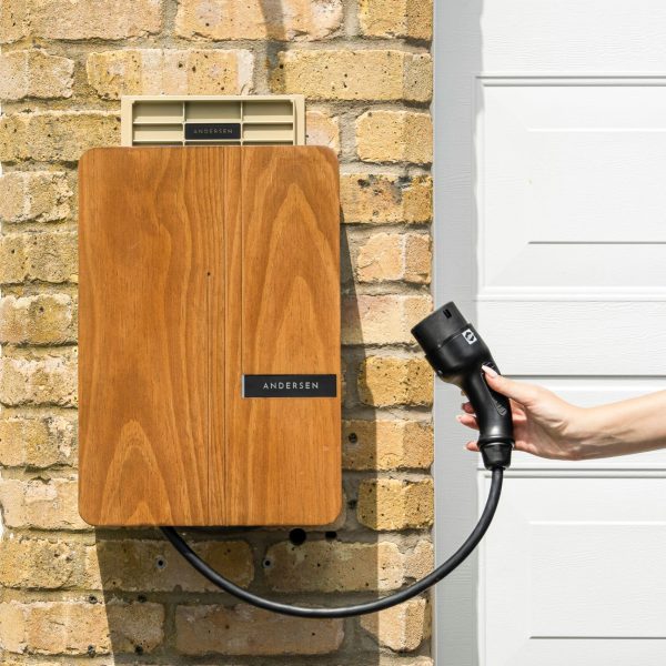 Wooden EV home charger installed on a brick wall for sustainable transportation.